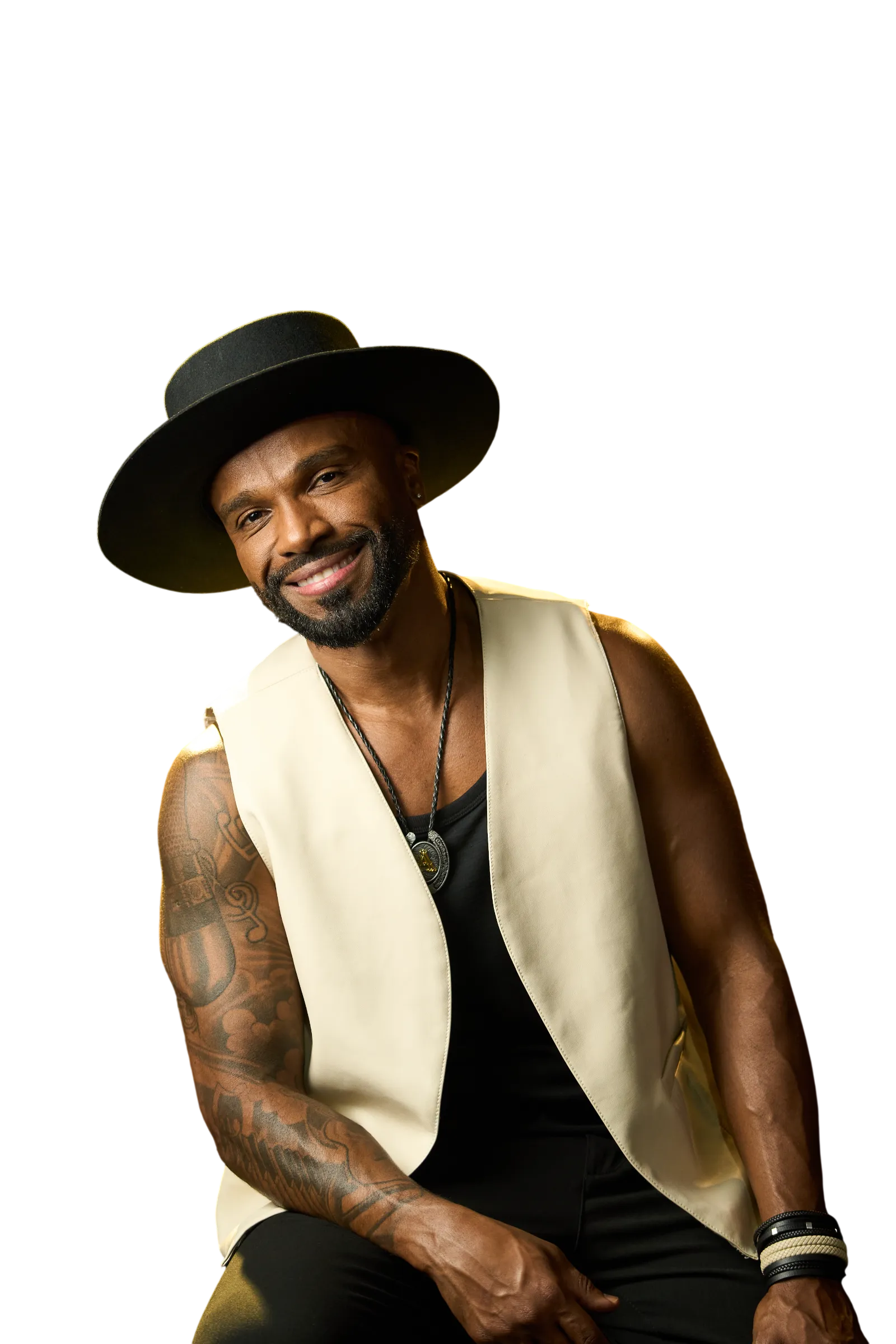Alexandre Pires sorrindo, de chapéu preto e colete creme